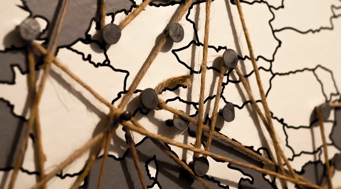 Karte mit Pins und dazwischengespanntem Faden als Symboldbild für das Internet